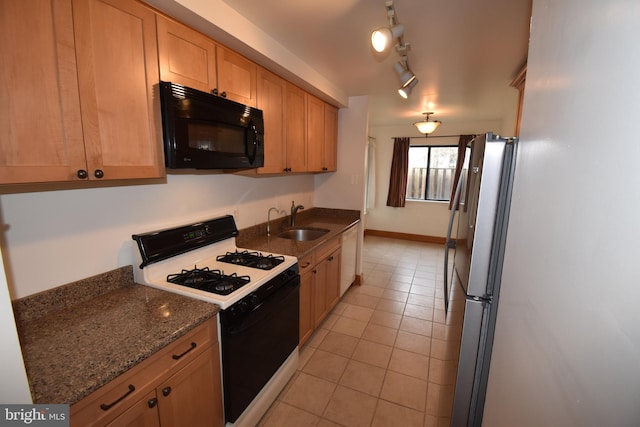 kitchen featuring light tile patterned flooring, sink, gas range, stainless steel fridge, and dark stone counters