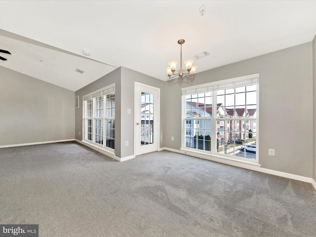 spare room featuring an inviting chandelier, lofted ceiling, and carpet floors