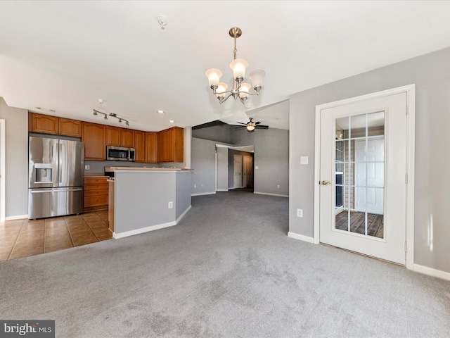 kitchen featuring hanging light fixtures, stainless steel appliances, carpet floors, track lighting, and ceiling fan with notable chandelier