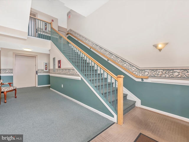 stairway with a towering ceiling and carpet flooring