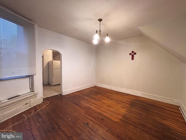 unfurnished dining area with lofted ceiling, hardwood / wood-style floors, and a notable chandelier