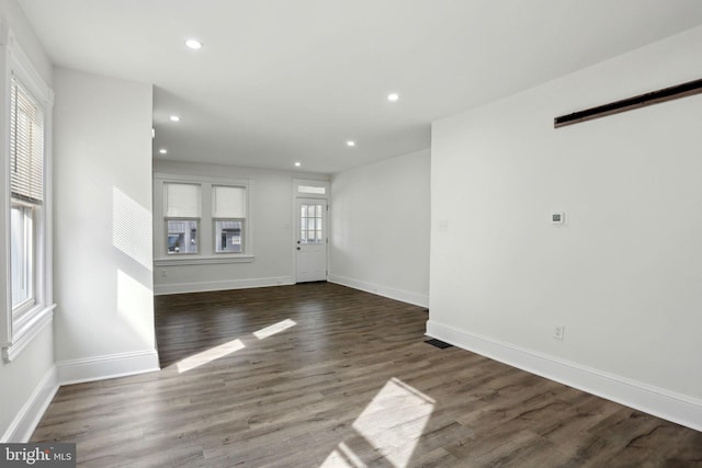 unfurnished living room featuring a barn door and dark hardwood / wood-style flooring