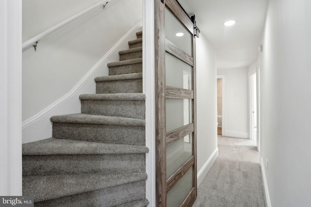 stairs featuring a barn door and carpet flooring