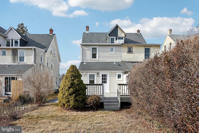 rear view of house featuring a deck and a lawn