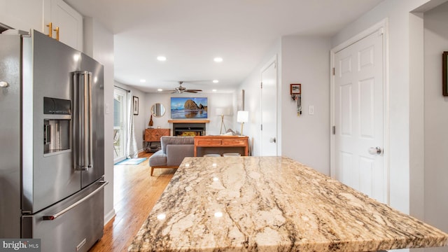 kitchen featuring high end fridge, light stone countertops, ceiling fan, and light wood-type flooring