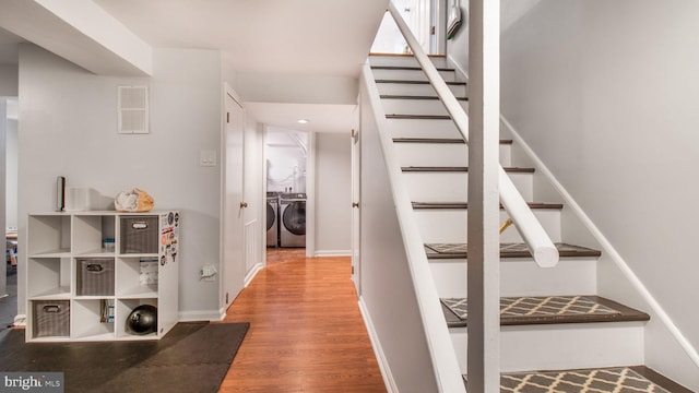 staircase with hardwood / wood-style floors and independent washer and dryer