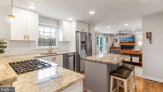 kitchen with white cabinetry, stainless steel appliances, sink, and light stone counters