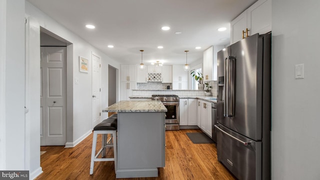 kitchen featuring white cabinetry, a breakfast bar area, stainless steel appliances, and a center island