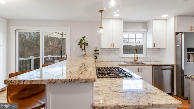 kitchen featuring appliances with stainless steel finishes, sink, pendant lighting, and white cabinets