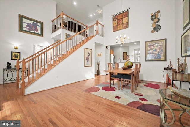 dining room with a towering ceiling, an inviting chandelier, and light hardwood / wood-style flooring