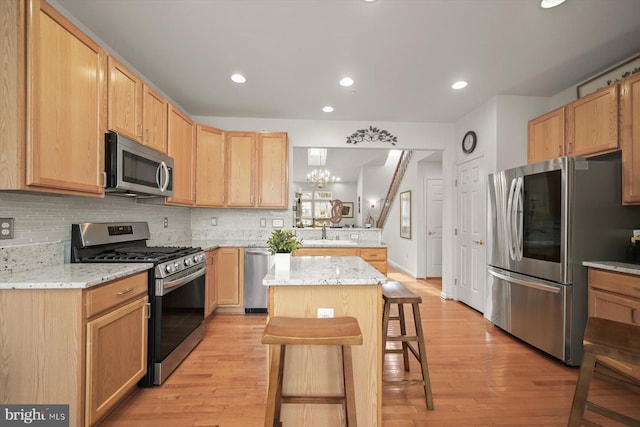 kitchen featuring a kitchen island, tasteful backsplash, a kitchen breakfast bar, stainless steel appliances, and light stone countertops