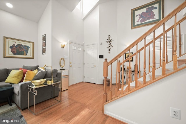 interior space with a towering ceiling, hardwood / wood-style floors, and a skylight