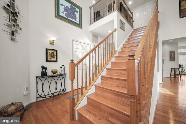 stairway with hardwood / wood-style floors and a high ceiling