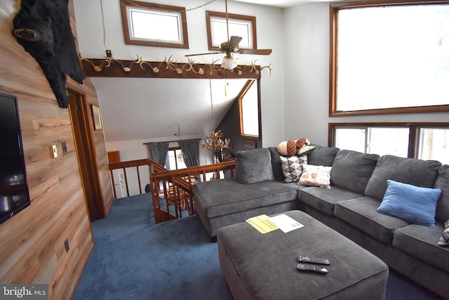 carpeted living room with wood walls, plenty of natural light, vaulted ceiling, and ceiling fan