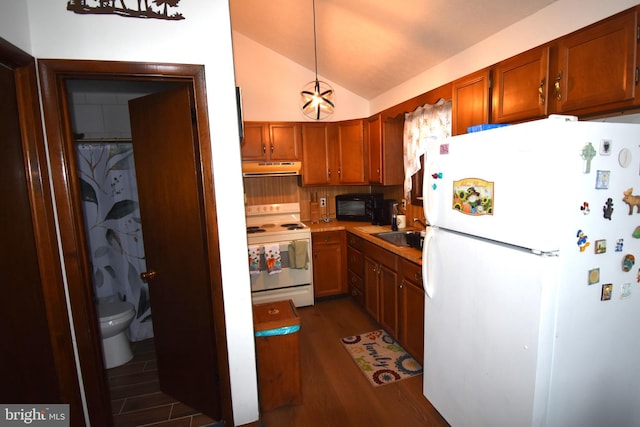 kitchen with white appliances, decorative light fixtures, vaulted ceiling, light countertops, and under cabinet range hood