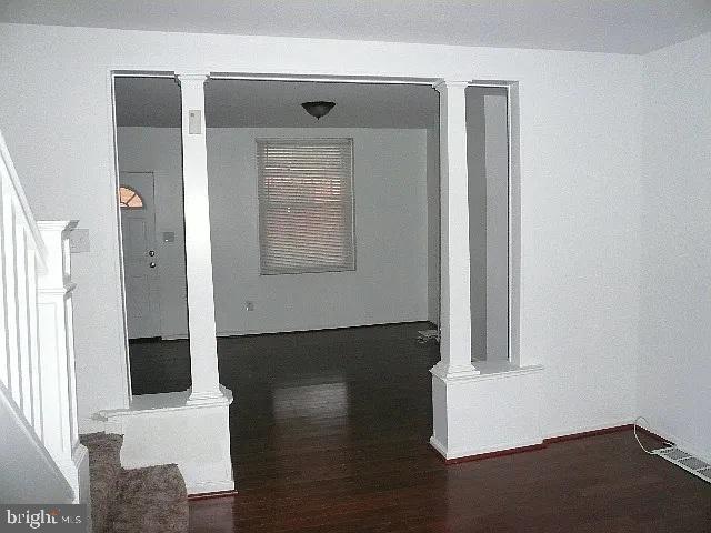 interior space with dark wood-type flooring and decorative columns