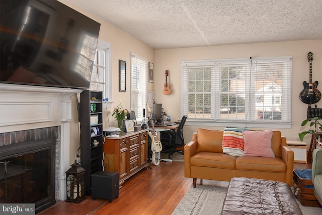 living area featuring a fireplace, a textured ceiling, and wood finished floors