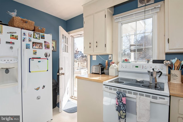 kitchen featuring white appliances, visible vents, and white cabinets