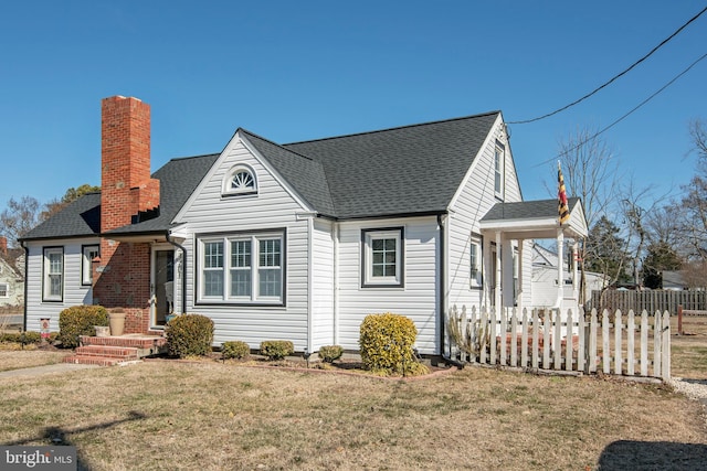 view of front of home featuring roof with shingles, a chimney, a front yard, and fence