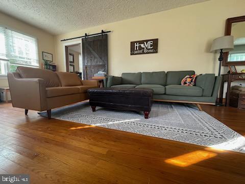 living room with a textured ceiling, a barn door, and hardwood / wood-style flooring