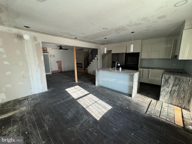 kitchen with sink, white cabinetry, pendant lighting, black double oven, and backsplash