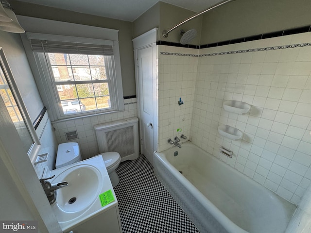 full bathroom featuring sink, tile walls, tiled shower / bath combo, radiator heating unit, and toilet