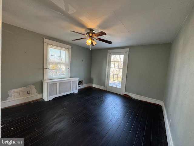 empty room with radiator, dark hardwood / wood-style floors, and ceiling fan