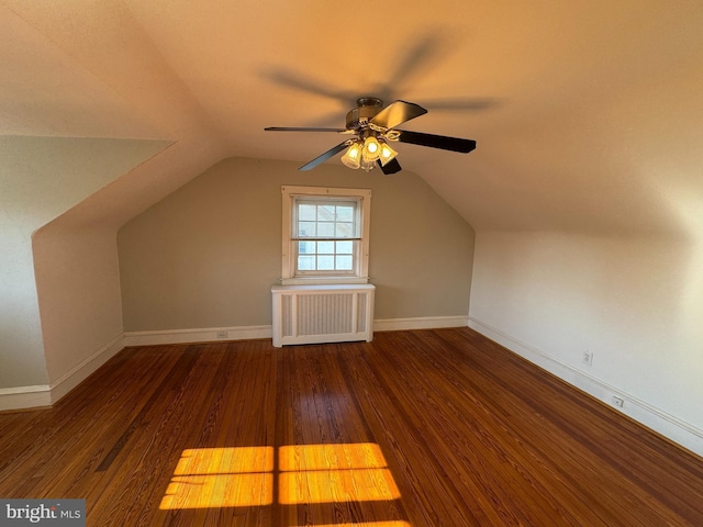 additional living space with vaulted ceiling, radiator, ceiling fan, and dark hardwood / wood-style floors