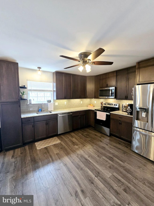 kitchen featuring sink, wood-type flooring, dark brown cabinets, appliances with stainless steel finishes, and backsplash