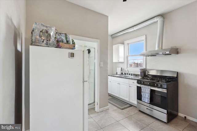 kitchen featuring light tile patterned flooring, stainless steel gas stove, white cabinetry, sink, and white fridge