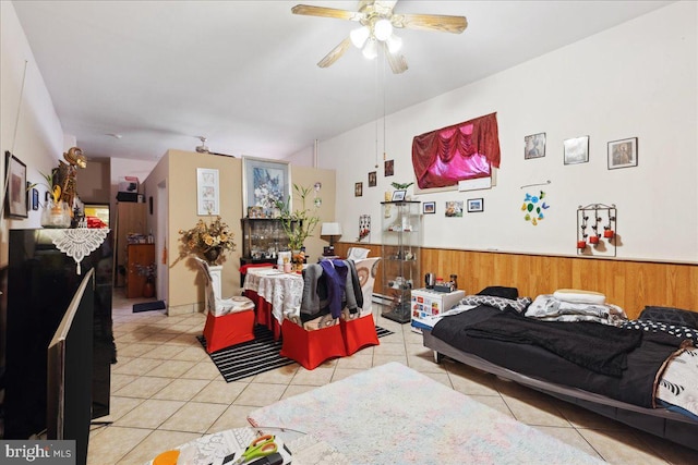 tiled living room featuring ceiling fan and wood walls