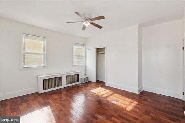 unfurnished bedroom with ceiling fan, radiator heating unit, dark hardwood / wood-style flooring, and a closet