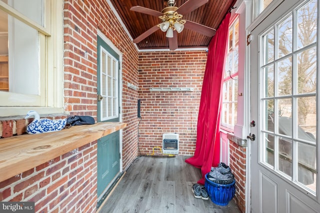 sunroom featuring ceiling fan, a wood stove, heating unit, and wooden ceiling