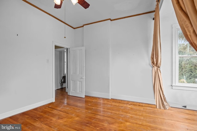 spare room with crown molding, a towering ceiling, ceiling fan, and light wood-type flooring