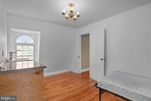 dining space with wood-type flooring, sink, and an inviting chandelier