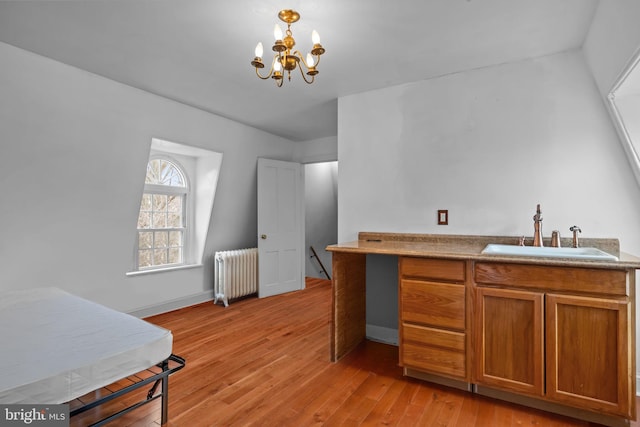 kitchen with an inviting chandelier, radiator heating unit, light hardwood / wood-style floors, and sink