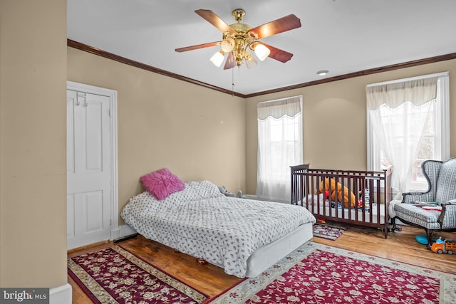 bedroom with hardwood / wood-style flooring, ceiling fan, and crown molding