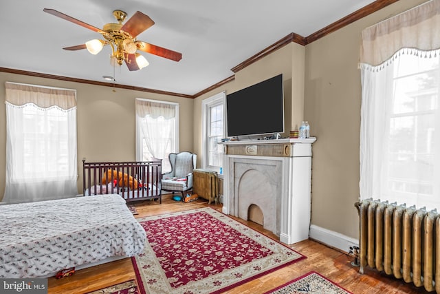 bedroom with radiator, light hardwood / wood-style flooring, ornamental molding, and ceiling fan