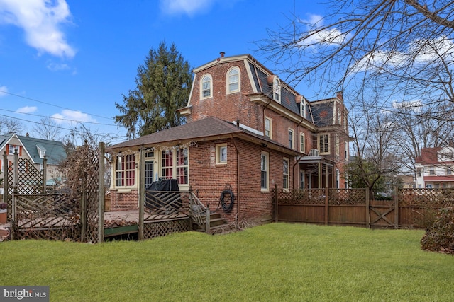 rear view of house with a wooden deck and a yard