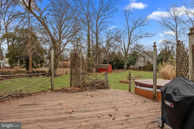 wooden deck featuring a grill, a yard, and a covered hot tub