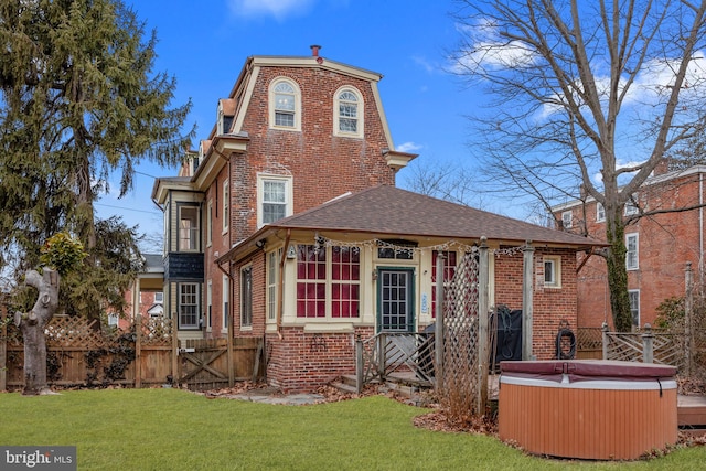 back of house featuring a lawn and a hot tub