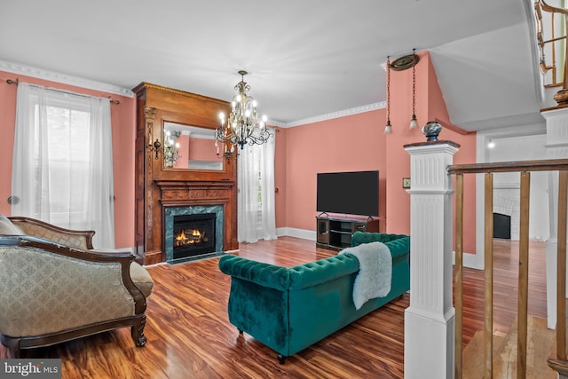 living room featuring crown molding, a high end fireplace, dark hardwood / wood-style flooring, and an inviting chandelier