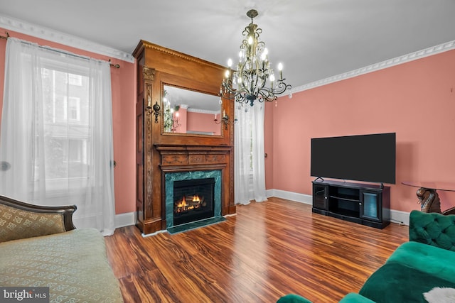 living room with a notable chandelier, hardwood / wood-style flooring, a fireplace, and ornamental molding