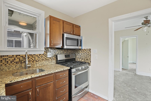 kitchen featuring light stone counters, sink, backsplash, and appliances with stainless steel finishes