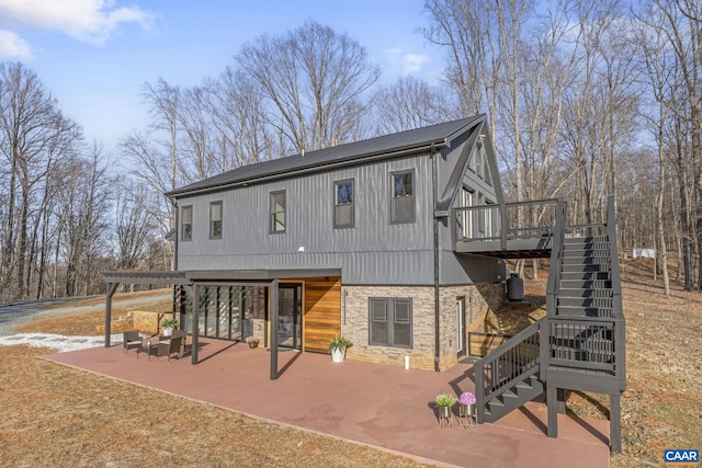 rear view of property featuring a wooden deck, a pergola, and a patio