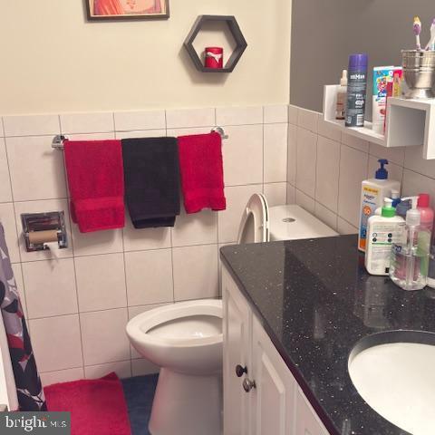 bathroom with sink, toilet, and tile walls