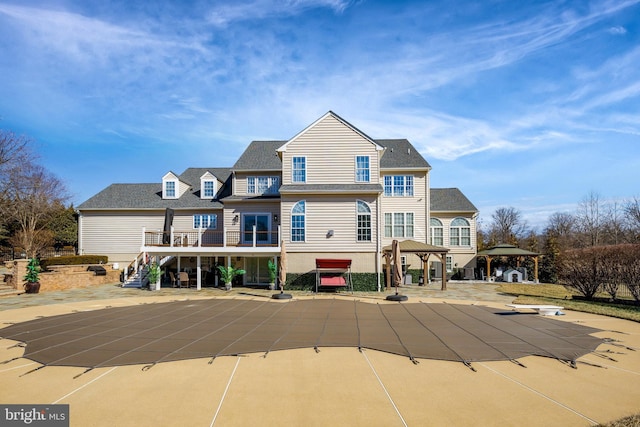 back of property featuring stairs, a gazebo, roof with shingles, a covered pool, and a patio area