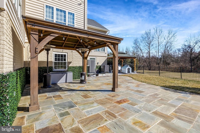 view of patio featuring a fenced backyard, an outbuilding, a storage unit, a gazebo, and central air condition unit