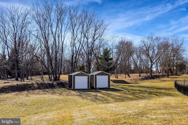 view of yard with a detached garage, fence, and an outdoor structure