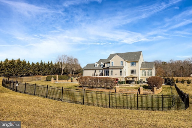 rear view of house featuring a fenced backyard, a rural view, a lawn, and a patio